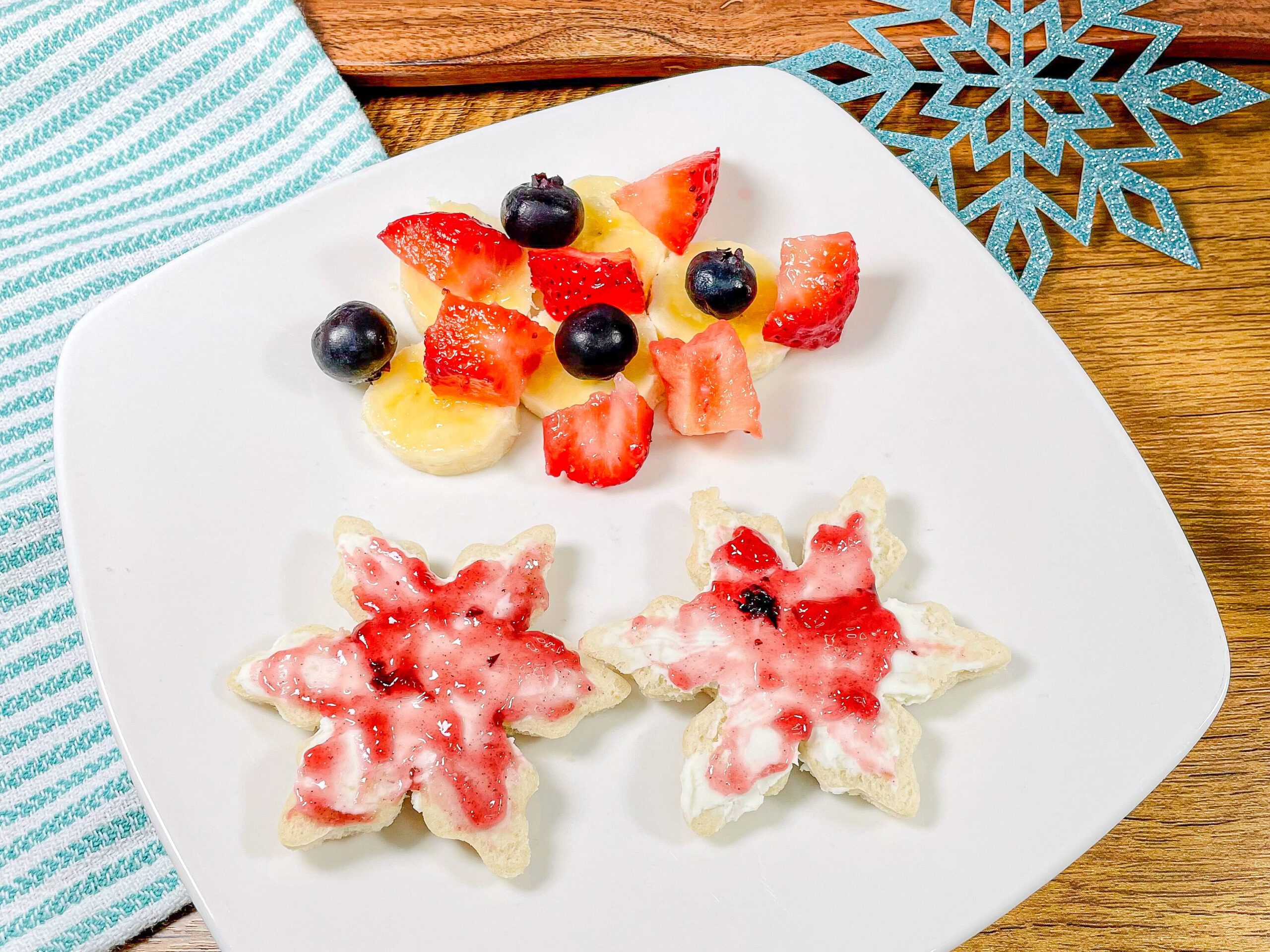 Pan con queso crema y mermelada de moras azules, acompañados de plátano, fresas y moras azules