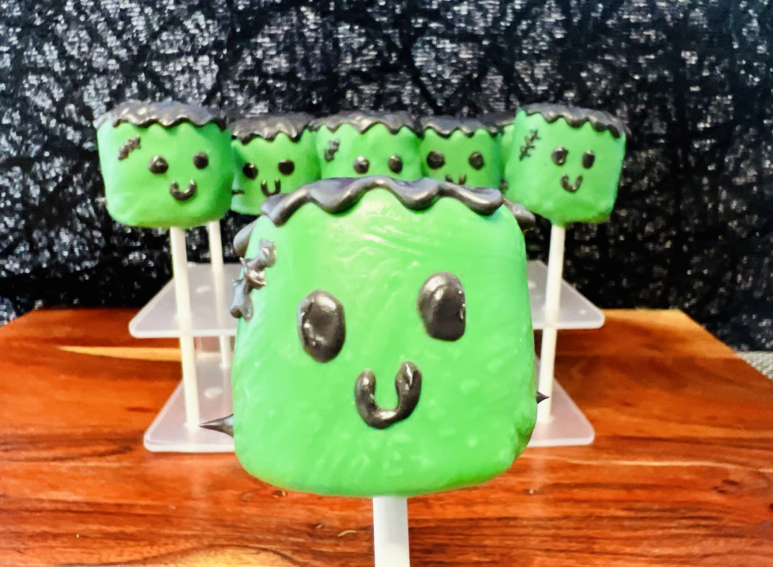 La imagen muestra una paleta d bombón de Frankenstein frente a un base con más paletas, con un fondo negro.