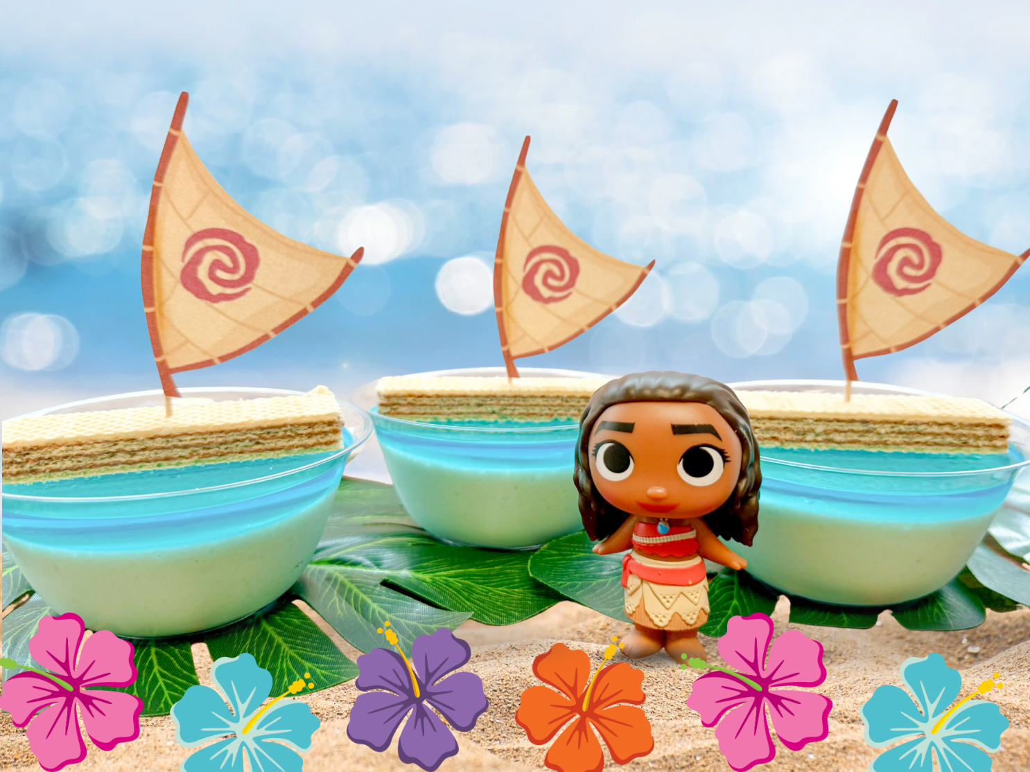La imagen muestra tres gelatinas azules en recipientes de plástico con una galleta con una vela insertada que simulan las canoas de Moana en el mar. Al frente hay una figura de Moana.